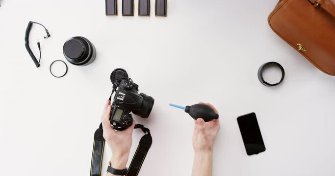 Photographer, cleaning camera and hand with sensor, lens and maintenance for equipment at media company. Person, photography gear and air pump for timelapse, dust and check with inspection at agency