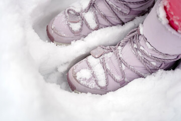 Purple puffed winter boots are standing in a deep snowdrift there is a lot of snow in winter