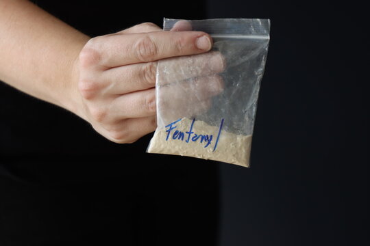 Woman holding a pack with fentanyl powder to illustrate the drug addiction 