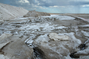 Natural salt flats. Industry and open cast mining. Saltworks and salt natural fields under a dramatic and stormy sky.	
