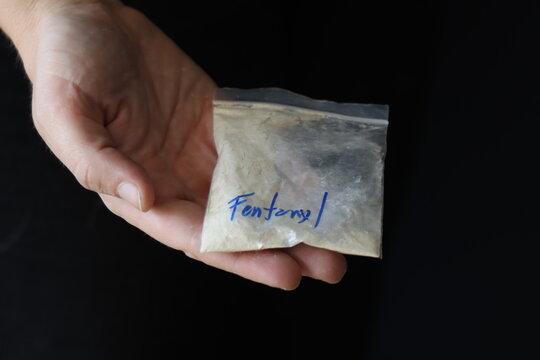 Woman holding a pack with fentanyl powder to illustrate the drug addiction 