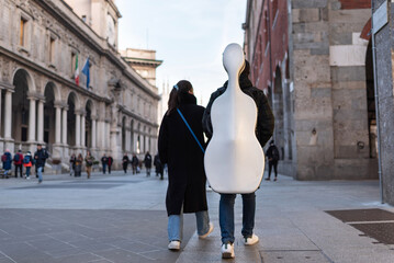 Musician walking with his instrument and his partner through Milan