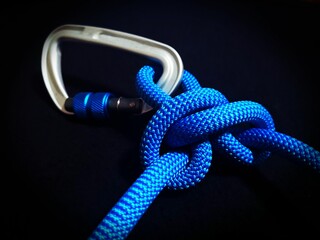 Vivid, close-up of a carabiner connector used for rock climbing on a solid black background
