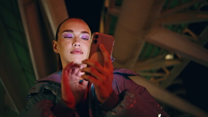 Trendy girl typing phone at night close up. Woman using smartphone to surfing.