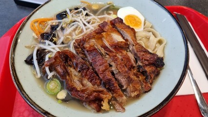 Ramen soup with fried duck, noodles, vegetables, eggs