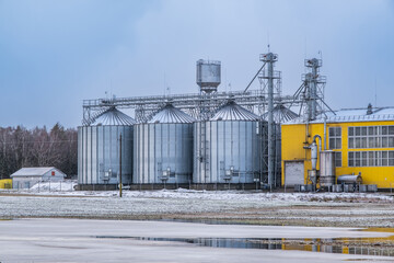 Obraz premium silos and agro-processing plant for processing for drying cleaning and storage and seed preparation complex in snow of winter field