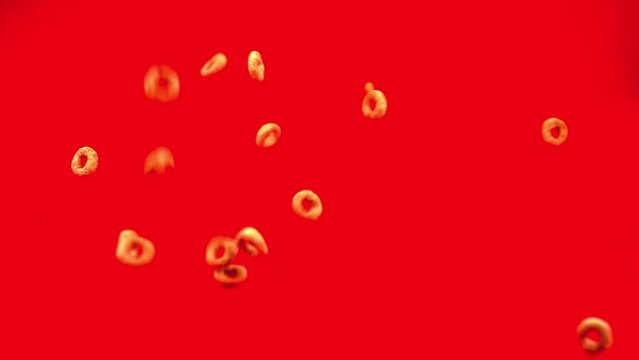 Small cheerios ring falling down to red background in slow motion