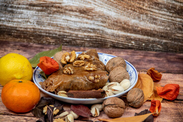 Turkish Baklava sweet cake on the plate, decorated with fresh pistachios, nuts, vanilla and dry autumn leaves, on wooden massive table  