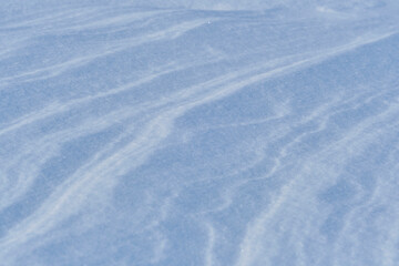 Snow after wind forms white canvas swirling patterns. Light, sparkling, with ice crystals. Unique natural texture and tranquility winter landscape.