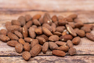 Close up roasted organic brown almond seed on wooden table and some of almond in white porcelain cup