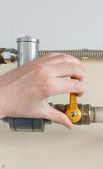 The locksmith's hand opening the acetylene supply valve on the gas pipe