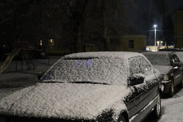 Car covered with snow in the night city, close-up