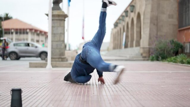 latin American breakdancer guy performing downrock or floor based footwork on the street