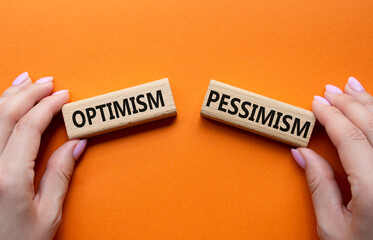 Optimism or Pessimism symbol. Concept word Optimism or Pessimism on wooden blocks. Businessman hand. Beautiful orange background. Business and Optimism or Pessimism concept. Copy space