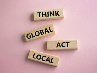 Think global act local symbol. Wooden blocks with words Think global act local. Beautiful pink...
