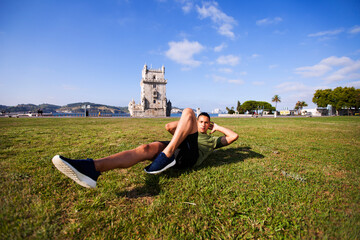 Young man doing exercise near Belém Tower - obrazy, fototapety, plakaty