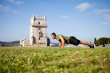 Young man doing exercise near Belém Tower - obrazy, fototapety, plakaty