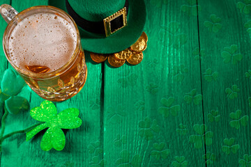 St. Patrick's day. Beer, leprechaun hat, gold and decorative clover leaves on green wooden table....
