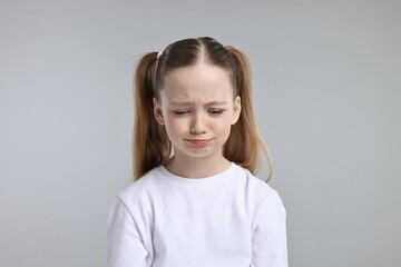 Portrait of sad girl on light grey background