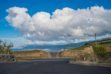Asphalt road at intersection overlooking the sea and mountain on the horizon in Ponta do Cintrão, São Miguel - Azores PORTUGAL