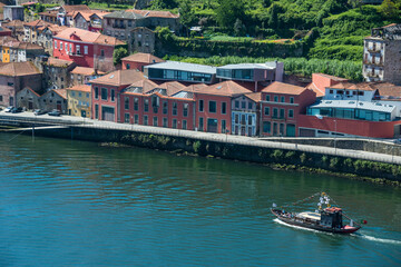 Buque de carga navegando por el río Duero frente a un grupo de casas en el centro de la ciudad de Oporto, Portugal - obrazy, fototapety, plakaty