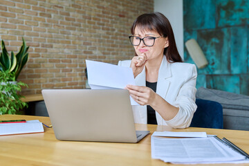 Upset sad business woman reading an official letter