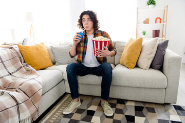 Full length photo of shocked funny guy dressed checkered shirt enjoying can cola pop corn watching...