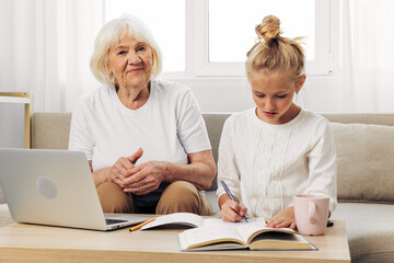Child granddaughter laptop call smiling education grandmother selfie togetherness hugging sofa bonding family video