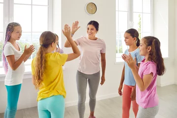 Store enrouleur tamisant sans perçage École de danse Happy female choreographer rejoicing the success of her students girls in dance training. Friendly woman teacher giving high five to her kids at the end of class in choreography studio.