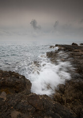 Fototapeta premium Windy waves splashing with power on a rocky coast in winter. Stormy weather outdoor