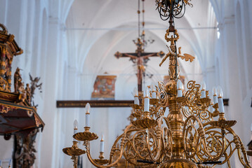 Golden chandelier with candlelike lights graces a church, showcasing Gothic design and a plain...