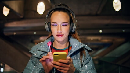 Woman listening music walking at night close up.Girl wearing wireless headphones