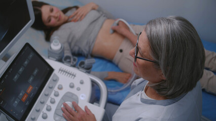 Female doctor conducts medical examination of stomach to female patient using sonography machine...