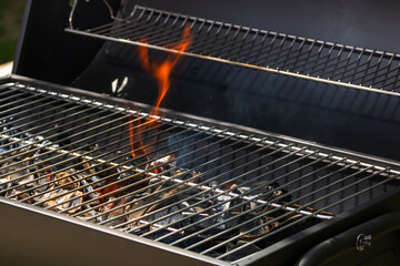 Barbecue grill pit with glowing and flaming hot open fire with red flame, hot charcoal briquettes...