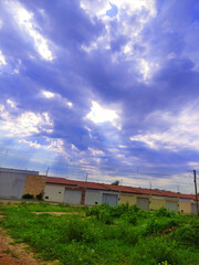 Fototapeta na wymiar Photo of blue sky with sunbeam over house and green vegetation.