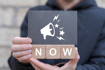 Man holding wooden cubes with icons and black sticky note with text: NOW. Now or later choice...