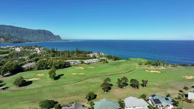 Aerial Kauai Hawaii luxury golf club homes Hanalei bay. Expensive luxury homes, resort, condominium and golf club near coast. Recreation and tourism. Green landscape. Economy tourism based.