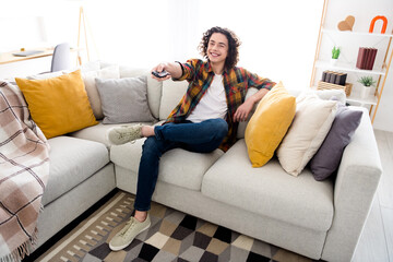 Full length photo of cheerful relaxing guy wear plaid shirt enjoying watching movie indoors room home house
