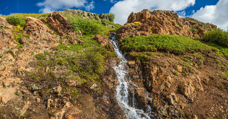 Naklejka na ściany i meble waterfall panorama with cliff rocks and green bushes