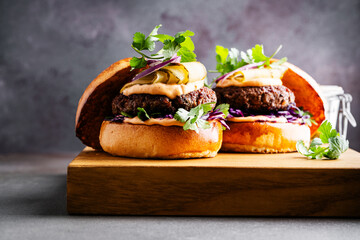 Beef burgers with pickles and red onion on cutting board