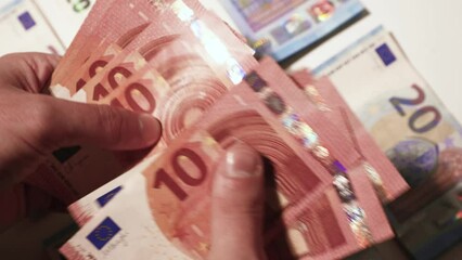 Counting the money in hands. 20 and 10 euro bills. Stacks of banknotes on the table. Close up stock slow motion video - Powered by Adobe