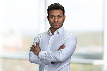 Portrait of young handsome businessman with arms crossed posing on blurred background. Attractive male ceo looking at camera.