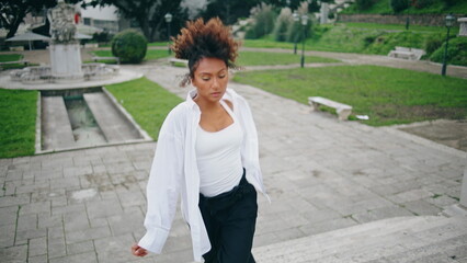 Vogue performer dancing stylishly on park stairs. Sexy girl moving seductively