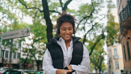 Girl listening music walk city in headphones closeup. African woman dancing song