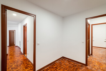 An apartment with corridor leading to empty rooms with wooden doors 