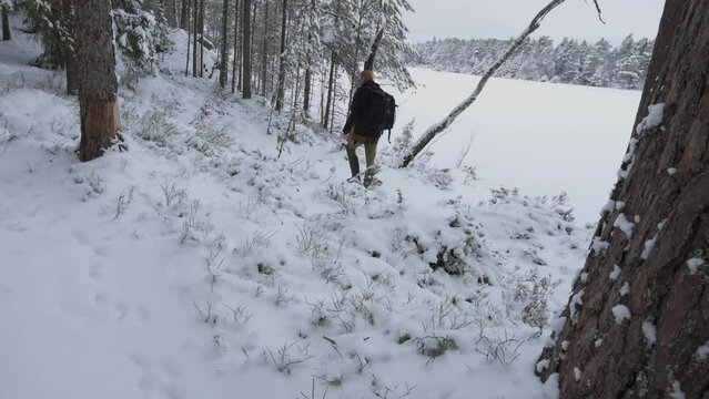 Man with backpack hiking in snowy winter forest