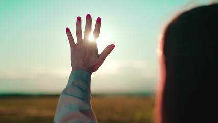 Hand of young girl reaches out to sun. Young woman extends her hand towards dawn. Sunlight between fingers of girls hand. Happy teenager dream, stretches out his hand to sun. Prayer to God sky peace