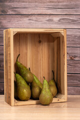 Juicy pears arranged in a wooden box on a wooden background, healthy juicy fruits,
