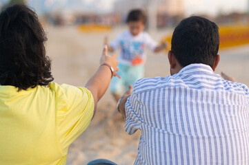 Indian family having fun with child boy on the beach. Family time together, happiness