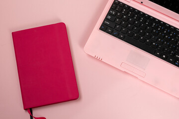 Pink laptop with pink notebook on pink background, feminine workplacep 